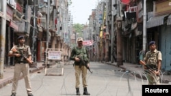 Indian security personnel stand guard along a deserted street during restrictions in Jammu, August 5, 2019.