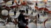 FILE - A woman wearing a mask to prevent the coronavirus is reflected in the mirrors, in Seoul, South Korea, Feb. 24, 2020.