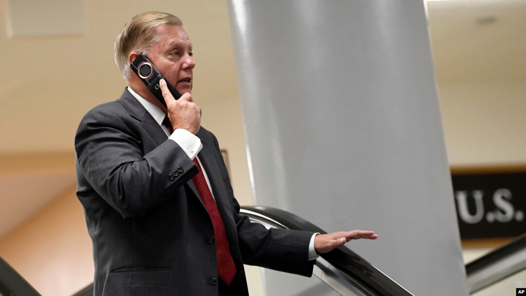 Sen. Lindsey Graham, R-S.C., talks on the phone as he rides the escalator on Capitol Hill in Washington, July 10, 2019, as he heads to a briefing on election security. 