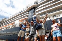 Para penumpang kapal pesiar Westerdam bersorak-sorai saat diperbolehkan turun di pelabuhan Sihanoukville, Kamboja, 14 Februari 2020.