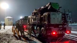 In this photo taken from video provided by the Russian Defense Ministry Press Service on Jan. 29, 2022, Russian military vehicles prepares to drive off a railway platforms after arrival in Belarus.