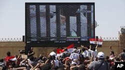 Egyptians follow the opening of the trial of ousted President Hosni Mubarak seen here on a TV screen as lay in the courtroom on a hospital bed. The broadcast of the trial, which began August 3, 2011, in Cairo, has since been suspended by the presiding jud