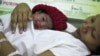 FILE - Danica Camacho is cuddled by her mother as they are wheeled out of the delivery room of the Government's Fabella Hospital moments after she was born October 31, 2011, in the Philippines.