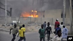 Smoke rises from police headquarters as people run for safety in Nigeria's northern city of Kano, Jan. 20, 2012.