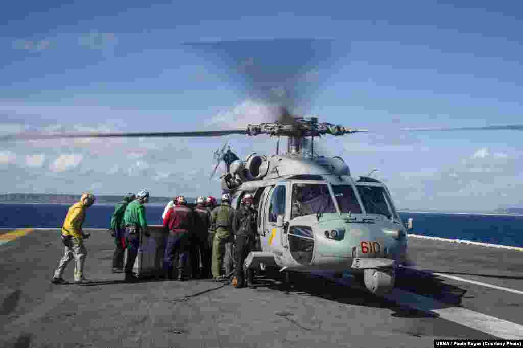 Sailors aboard the U.S. Navy's forward-deployed aircraft carrier USS George Washington load containers of water onto an MH-60S Seahawk, Nov. 15, 2013. (U.S. Navy)