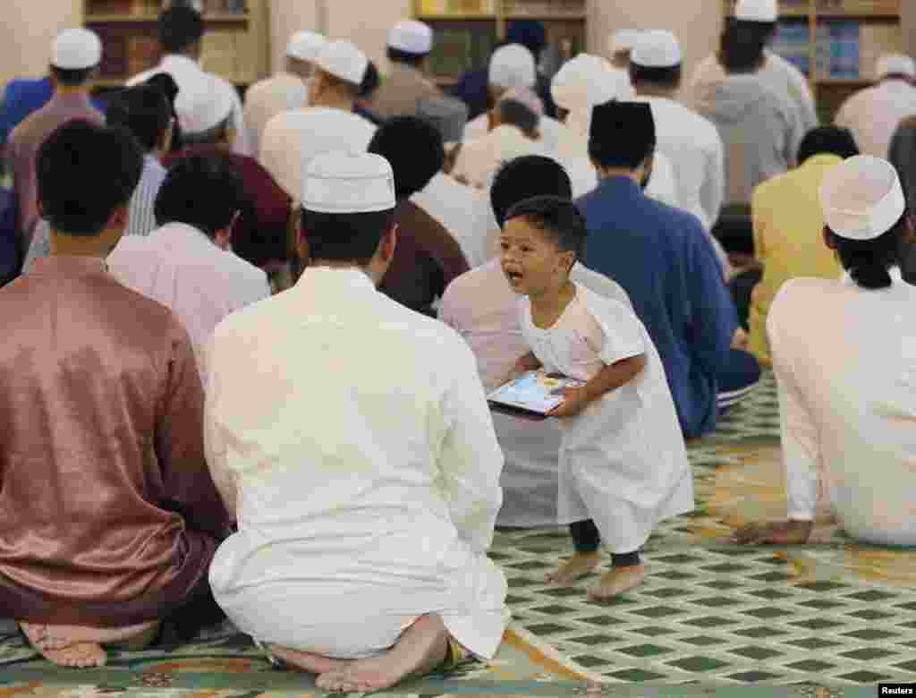 Seorang anak memanggil ayahnya ketika sedang shalat tarawih pertama di Kuala Lumpur, Malaysia (17/6). (Reuters/Olivia Harris)