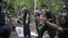 Policemen monitor as forensic experts dig out human remains near the abandoned human trafficking camp in the jungle close the Thailand border at Bukit Wang Burma in northern Malaysia May 26, 2015. Malaysian police forensic teams, digging with hoes and sho