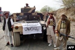 FILE - Armed militants of Tehrik-i-Taliban Pakistan (TTP) pose for photographs next to a captured armored vehicle in the Pakistan-Afghanistan border town of Landikotal, Nov. 10, 2008.