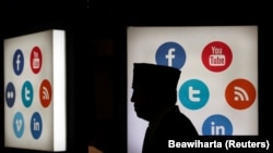 Seorang pria berjalan melintas di depan logo media sosial di Jakarta Convention Center, Jakarta,16 Mei 2016. (Foto: REUTERS/Beawiharta)