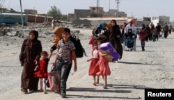 Para warga yang melarikan diri dari rumah mereka karena konflik antara pasukan Irak dan militan ISIS kembali ke desa mereka yang sudah dibersihkan oleh pasukan Irak di bagian barat Mosul, di Irak, 7 June 2017.