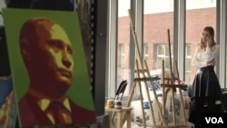 An activist is seen talking on her phone at the office of pro-Kremlin youth group SET (Network). To her left is a portrait of Russian President Vladimir Putin. (VOA video screengrab)