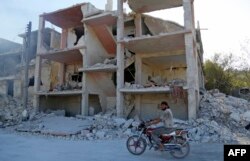 Sirijac vozi motocikl pored uništene zgrade u oblasti za koju se javlja da je pogođena tokom vazdušnog napada u Džisr al Šuguru, u provinciji Idlib, 4. septembra 2018.