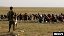 Seorang pejuang Pasukan Demokratis Suriah (SDF) yang didukung AS mengawasi para tawanan dan warga sipil di Baghouz, provinsi Deir Al Zor, Suriah.