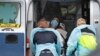 13일 미국 매사추세츠주 첼시의 한 진료소에서 신종 코로나바이러스 감염 의심 환자를 구급차에 태우고 있다.