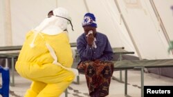 Petugas kesehatan mengenakan pakaian pelindung sedang menangani pasien Ebola yang baru masuk zona karantina di fasilitas Palang Merah di Kota Koidu, Distrik Kono, sebelah selatan Sierra Leone, 19 Desember 2014. 
