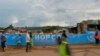 FILE - People walk across a bridge with a message written on the barriers advocating personal efforts to stem the spread of the COVID-19 coronavirus in the Kibera slum, Nairobi, on April 14, 2020. 