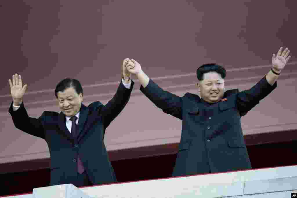 朝鲜领导人金正恩同中共政治局常委同刘云山在平壤的朝鲜"劳动党"建党70周年阅兵式上携手(2015年10月10日)。