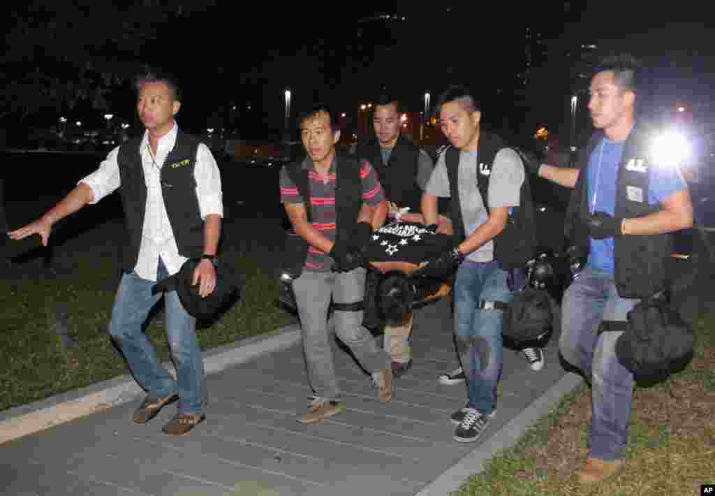 Ken Tsang (center), a member of a local pro-democracy political party, is carried by plainclothes police officers after a clash between protesters and police near the government headquarters in Hong Kong, Oct. 15, 2014.