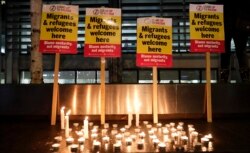 FILE - Signs and candles on a wall were placed at a vigil for the 39 smuggling victims found dead in a truck in an industrial park in England, outside the Home Office in London, Oct. 24, 2019.