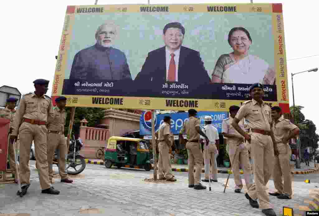 Police personnel stand guard in front of a billboard with images of India's Prime Minister Narendra Modi, China's President Xi Jinping and Anandiben Patel, Chief Minister of the western Indian state of Gujarat, ahead of Xi's arrival in Ahmedabad, Sept. 16, 2014.