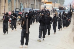 FILE - Islamic State of Iraq and the Levant fighters carry their weapons during a parade at the Syrian town of Tel Abyad, near the border with Turkey, Jan. 2, 2014.