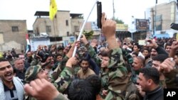 Para demonstran meneriakkan slogan-slogan dan mengacungkan senjata dalam sebuah demo menuntut penarikan pasukan Turki dari Basra, Irak, 12 Desember 2015.