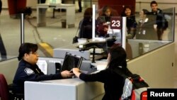 Seorang penumpang maskapai asing disambut oleh Petugas Perlindungan Bea dan Cukai di Bandara Internasional Hartsfield-Jackson di Atlanta, Georgia, 5 Januari 2004. (Foto: dok).