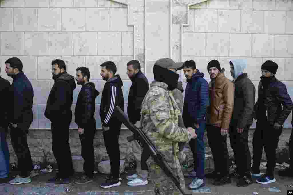 Members from ousted President Bashar al-Assad's Syrian army line up to register with rebels as part of a "identification and reconciliation process" at a army compound in Latakia.