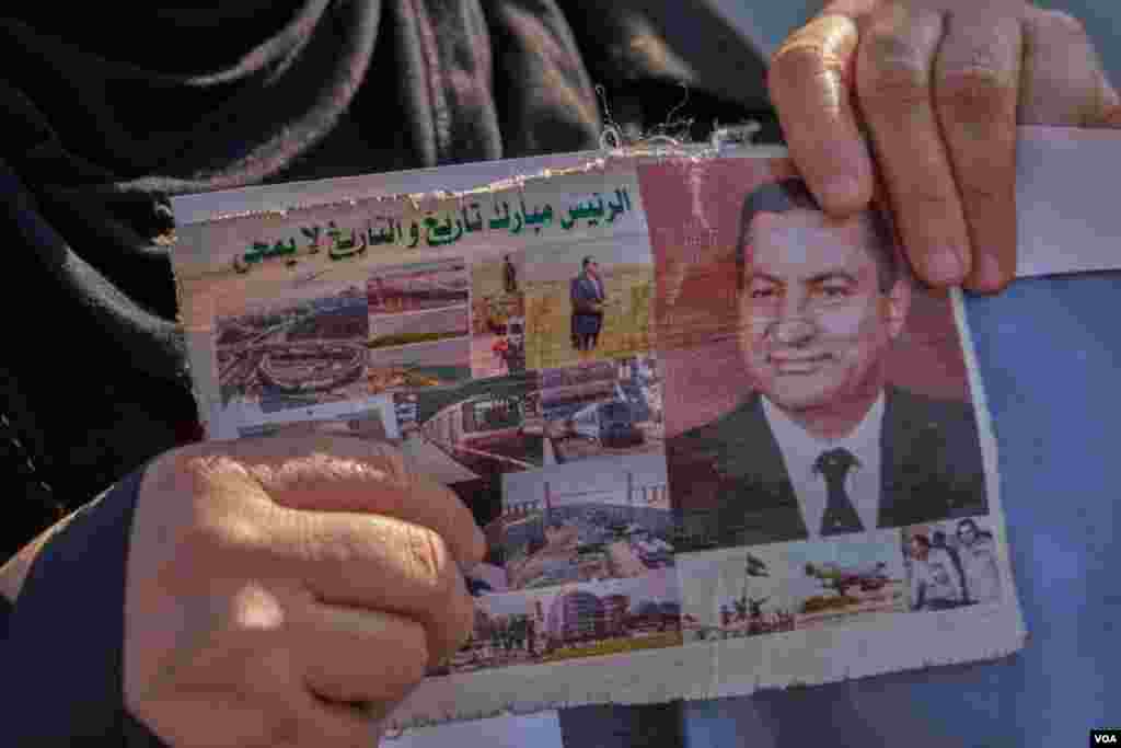 A mourner holds a card with pictures depicting Egypt's modernization. In his three decades as president, Mubarak initiated major infrastructure projects such as Cairo's Ring Road, the capital's subway system, and other projects. (Hamada Elrasam/VOA)