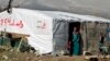 FILE - A woman stands outside her tent in a Syrian refugee camp in Houch al-Harimeh, Lebanon. Refugees in Syria’s neighboring countries often live in terrible conditions, spurring many to attempt the journey to Europe.