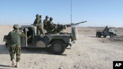 FILE - Afghan National Army soldiers stand guard at a checkpoint on the way to the Sangin district of Helmand province, Afghanistan, Dec. 23, 2015.