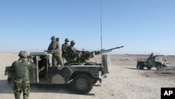 FILE - Afghan National Army soldiers stand guard at a checkpoint on the way to the Sangin district of Helmand province, Afghanistan, Dec. 23, 2015.