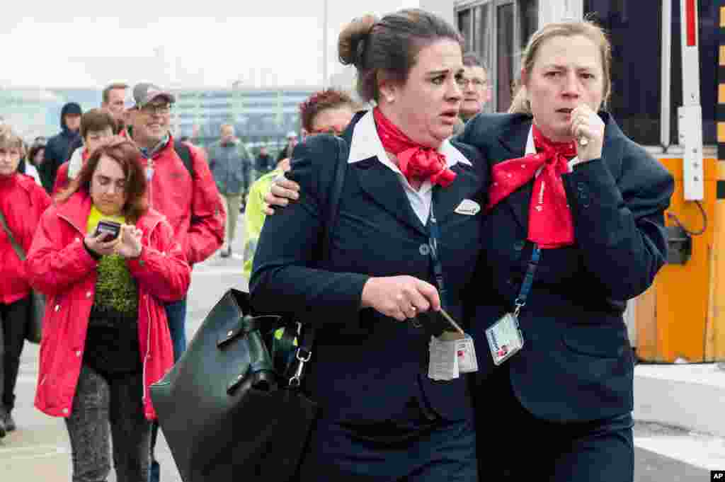 People react as they walk away from Brussels airport after explosions rocked the facility in Brussels, Belgium, March 22, 2016.