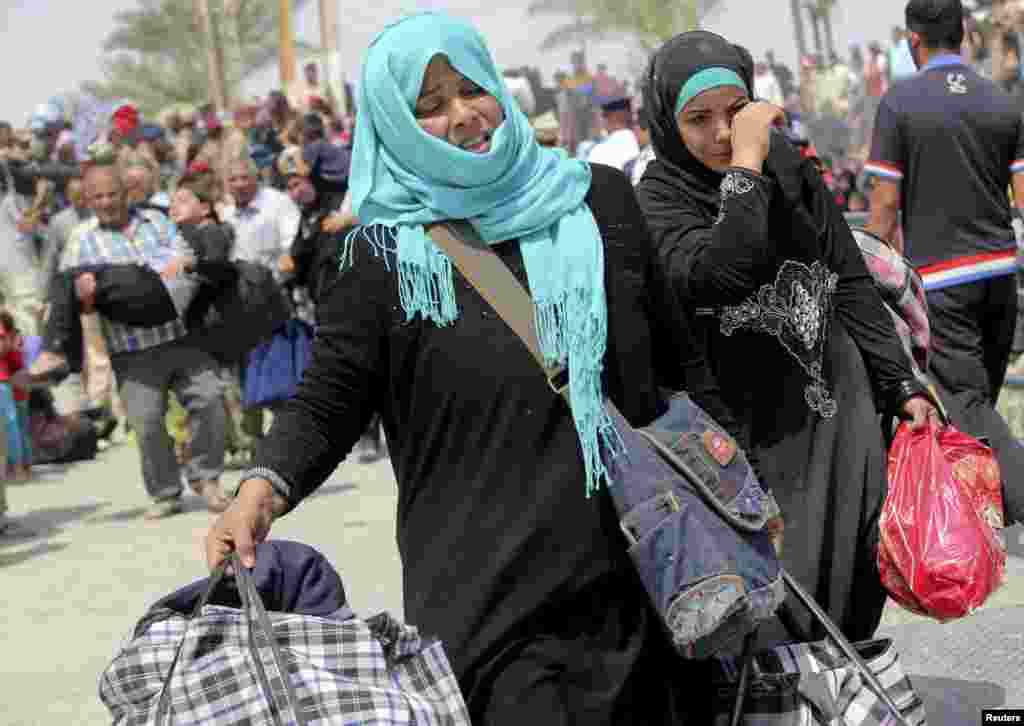 Displaced Sunni women fleeing the violence in Ramadi carry bags as they walk on the outskirts of Baghdad, May 24, 2015.