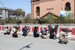 FILE- Afghan journalists work behind a barrier at the site of an attack on the Telecommunication Ministry in Kabul, April 20, 2019. Limiting access to information by the Afghan government is not acceptable, said an official from an Afghan watchdog.