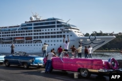FILE - Cubans watch as the first U.S.-to-Cuba cruise ship to arrive in the island nation in decades glides into the port of Havana, May 2, 2016.