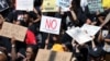 FILE - Women hold placards as they protest against gender-based violence, outside the Johannesburg Stock Exchange in Sandton, Johannesburg, South Africa, Sept. 13, 2019. 