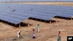 Buruh di India bekerja dekat panel tenaga surya di Gujarat Solar Park di Charanka, distrik Patan. 