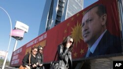 Warga melintas dalam papan reklame besar dengan foto Presiden Turki, Recep Tayyip Erdogan, yang berbunyi “Ya” dalam bahasa Turki di Ankara, Turki, 22 Maret 2017 (foto: AP Photo/ Burhan Ozbilici)