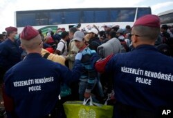 Hungarian police officers stop a group of migrants before a bus that would take the migrants in Roszke, southern Hungary, Sept. 8, 2015.