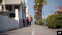 People walk along the promenade in the seaside town of Ostia, near Rome, April 13, 2020.