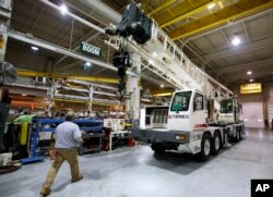 FILE - A worker walks past a crane on the assembly line at the Terex Corporation plant in Waverly, Iowa.