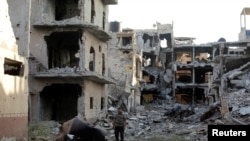FILE - A man stands next to destroyed and damaged buildings in Sabri, a central Benghazi district, Libya, Aug. 15, 2017.