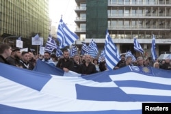 Protesters hold a Greek flag during a rally against the use of the term "Macedonia" in any settlement to a dispute between Athens and Skopje over the former Yugoslav republic's name, in Athens, Greece, Feb. 4, 2018.