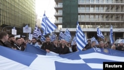 FILE - Protesters hold a Greek flag during a rally against the use of the term "Macedonia" in any settlement to a dispute between Athens and Skopje over the former Yugoslav republic's name, in Athens, Greece, Feb. 4, 2018. 