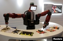 FILE - A Baxter robot of Rethink Robotics picks up a business card as it performs during a display at the World Economic Forum (WEF), in China's port city Dalian, Liaoning province, China onSept. 9, 2015.