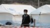A man wearing a protective face mask walks at a new temporary camp for migrants and refugees, on the island of Lesbos, Greece, Sept. 19, 2020. 