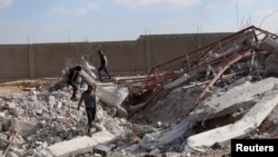 FILE - Youth inspect rubble of a damaged house after an airstrike on rebel-held Daraa al-Balad, Syria, April 7, 2017. 