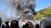 Migrants watch smoke rising from a fire inside a refugee camp on the eastern Aegean island of Samos, Greece, Nov. 11, 2020. 