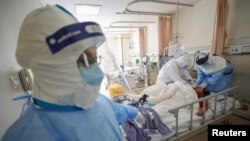 Trabajadores médicos fuertemente protegidos atienden a pacientes de coronavirus en la ciudad china de Wuhan, el 17 de febrero de 2020.